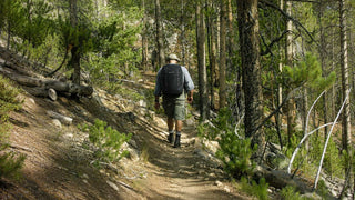 Man rucking through a forest trail carrying a weighted backpack