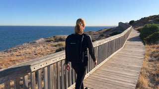 Woman rucking along a coastal boardwalk wearing a Ruckaway backpack