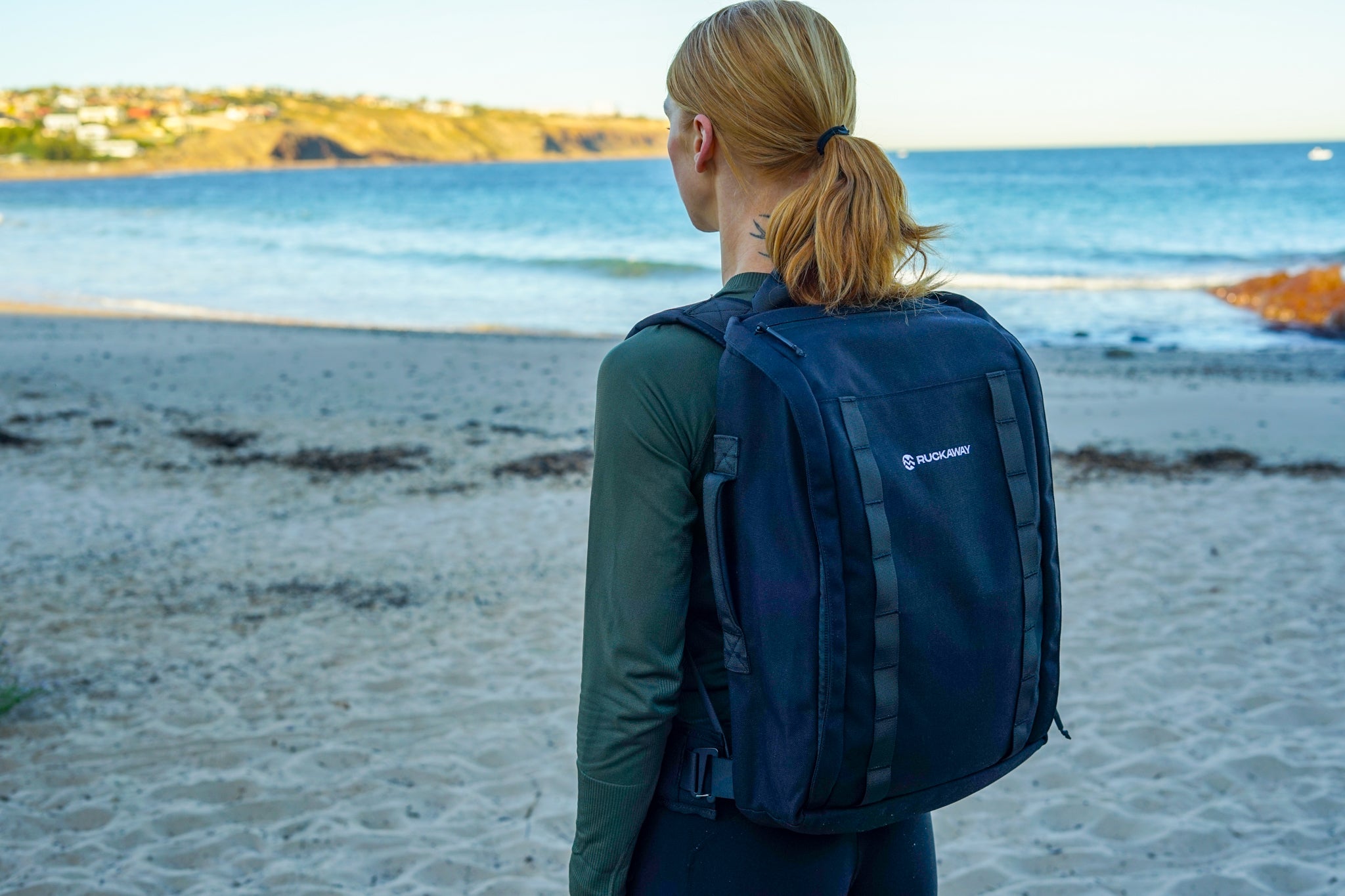 Woman rucking on beach wearing Ruckaway backpack