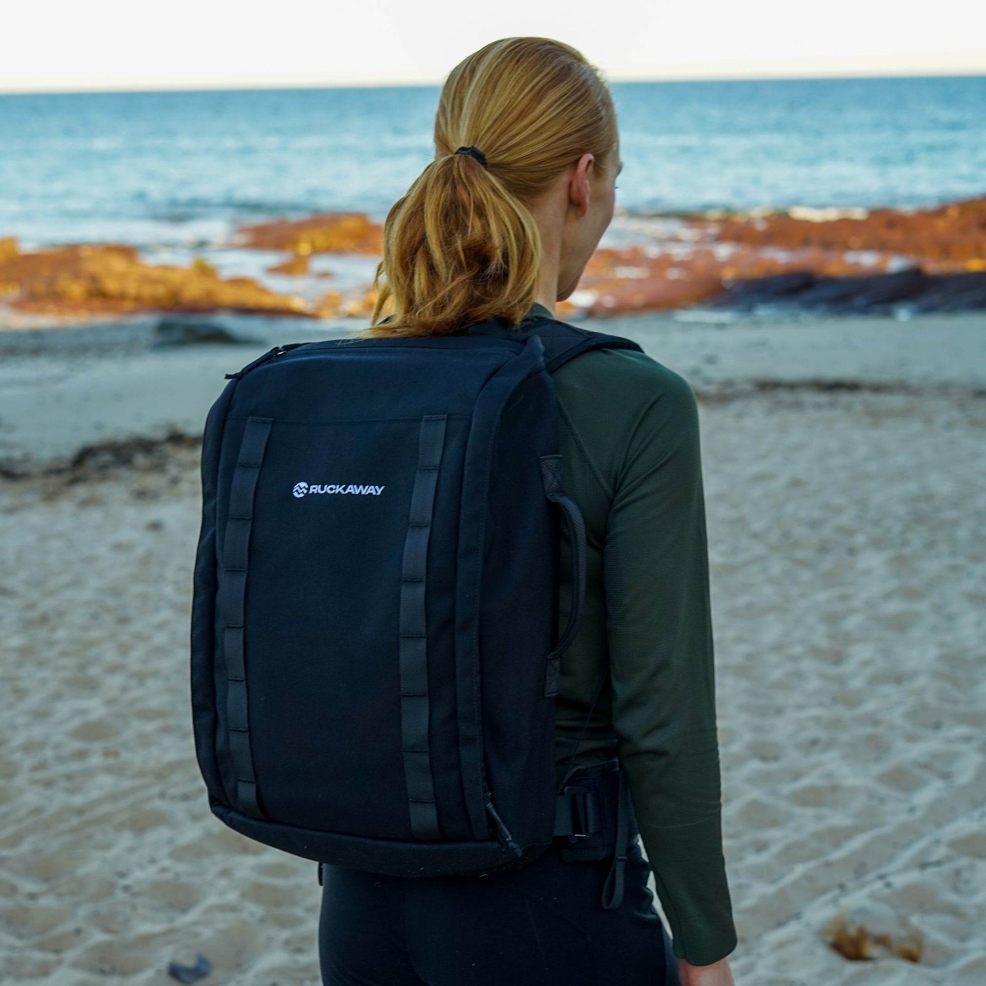 Woman rucking on beach wearing Ruckaway weighted backpack